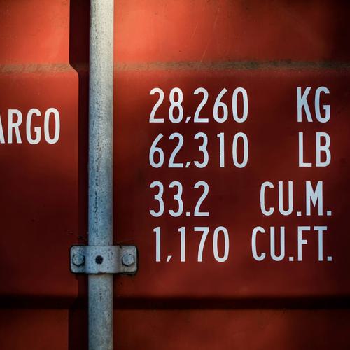 The back of a red cargo container shows identifying weights and measurements.