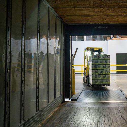 A forklift loading a truck. The image is taken from the inside of the truck.