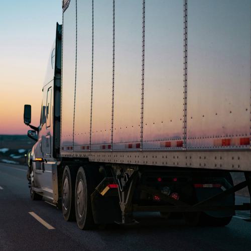 Semi-truck driving off into a sunset.